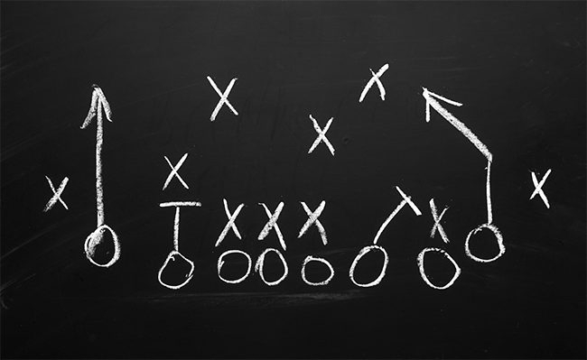A gameplan with Xs and Os in white chalk on a black chalkboard